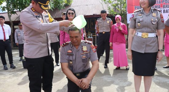 Kapolres Kotamobagu AKBP Dasveri Abdi melakukan penyiraman kepada Kapolsek Kotamobagu AKP Luther Tadung, usai upacara kenaikan pangkat, Sabtu (31/12/2022). (Foto: Miranty Manangin)