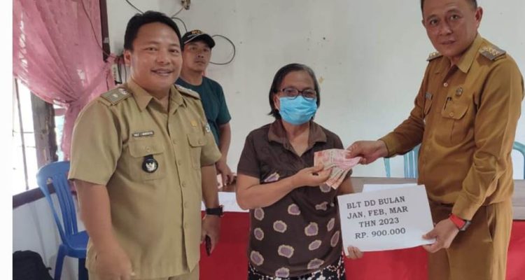 Hukum Tua Desa Pinamorongan Kecamatan Tareran Kabupaten Minahasa Selatan, Dolly Marentek bersama camat Tareran,Hizkia Kondoj, menyalurkan BLT DD kepada salah satu KPM di Kantor Desa setempat, Selasa (18/4/2023). Foto: Jendry Paendong