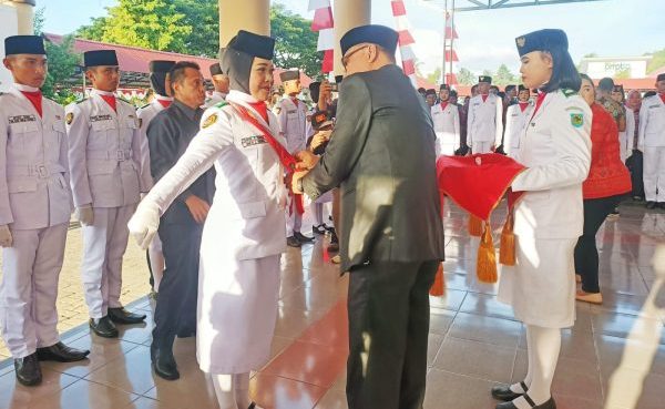 Tampak Penjabat Bupati Bolmong Limi Mokodompit saat penyematan kendit kepada salah satu anggota Paskibraka, sebagai tanda telah dikukuhkannya Paskibraka HUT ke 78 Kemerdekaan RI, di Halaman Kantor Bupati Bolmong, Lolak, Selasa 15 Agustus 2023. (foto.Diskominfo Bolmong)