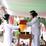 Wali Kota Kotamobagu Tatong Bara menyerahkan Bendera Merah Putih kepada Paskibraka pada peringatan HUT RI Ke-78 yang digelar di Lapangan Aruman Jaya, Kelurahan Motoboi Kecil, Kamis (17/8/2023). Foto: dok/Diskominfo Kotamobagu.