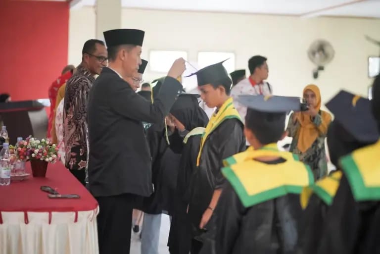 Bupati Bolsel, Iskandar Kamaru, memindahkan Tali Toga pada acara wisuda santri cilik Kabupaten Bolsel, Kamis (21/12/2023). Foto: Wawan Dentaw/bolmong.news
