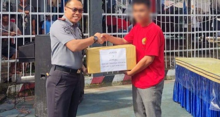 Karutan Kotamobagu Aris Supriyadi (kiri), saat menyerahkan langsung hadiah kepada salah satu warga binaan pemenang lomba di Pekan Olahraga WBP, di Lapangan Utama Rutan Kotamobagu, Senin 4 Maret 2024. (Foto.Ilham/Rutan Kotamobagu)