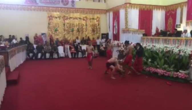 Foto yang diambil dari potongan video yang beredar dengan jelas memperlihatkan bagaimana Uwin menebas kaki Yudi sang penari dalam pentas Tari Mosau pada perayaan HUT Bolmong ke-70 yang digelar di gedung DPRD Kabupaten Bolmong, Senin (25/3/2024). Foto: Capture video