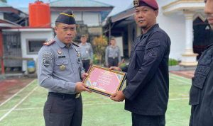 Karutan Kotamobagu Aris Supriyadi (kiri), saat menyerahkan Piagam Penghargaan kepada salah satu Pegawai terbaik Rutan, di Lapangan Utama Rutan, Senin 1 Juni 2024. (Foto.Ilham/Rutan Kotamobagu)