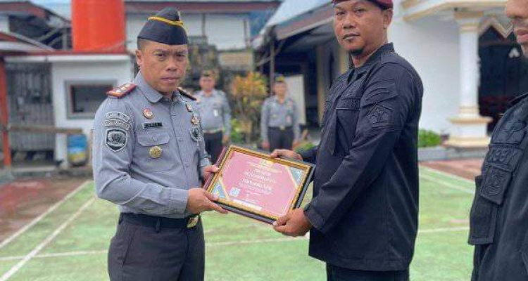 Karutan Kotamobagu Aris Supriyadi (kiri), saat menyerahkan Piagam Penghargaan kepada salah satu Pegawai terbaik Rutan, di Lapangan Utama Rutan, Senin 1 Juni 2024. (Foto.Ilham/Rutan Kotamobagu)