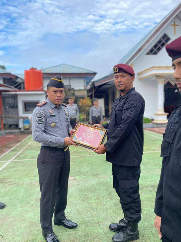 Karutan Kotamobagu Aris Supriyadi (kiri), saat menyerahkan Piagam Penghargaan kepada salah satu Pegawai terbaik Rutan, di Lapangan Utama Rutan, Senin 1 Juni 2024. (Foto.Ilham/Rutan Kotamobagu)