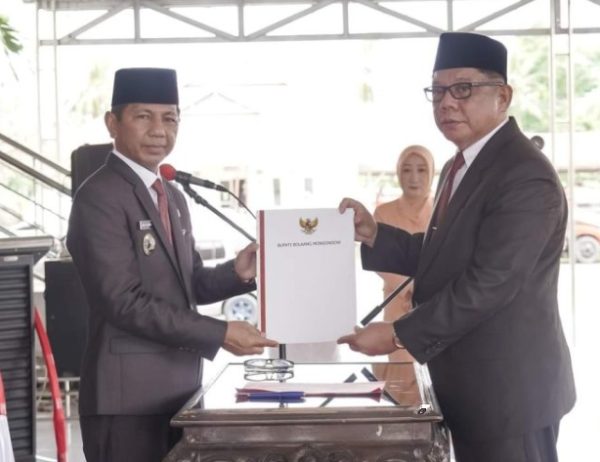 Penjabat Bupati Bolmong dr Jusnan Calamento Mokoginta MARS (kiri), saat menyerahkan SK Bupati pada Sekda Definitif Abdullah Mokoginta, di Pelataran Kantor Bupati Bolmong, Lolak, Senin 8 Juli 2024. (Foto.Istimewa/Diskominfo Bolmong)