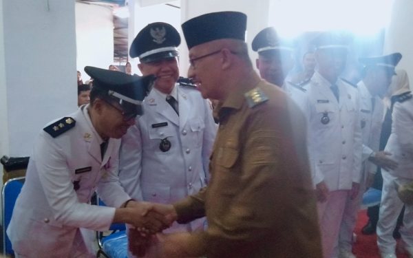 Pj Wali Kota Kotamobagu Asripan Nani, saat memberikan selamat kepada Sangadi Moyag Todulan Roliadi Modeong (kiri), usai acara penyerahan SK dan pengukuhan perpanjangan masa jabatan, di aula rumah dinas Wali Kota Kotamobagu, Senin 5 Agustus 2024, siang tadi. (foto.Wahyudy Paputungan/bolmong.news)