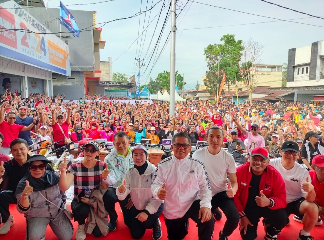 Tampak pasangan calon Wali Kota dan Wakil Wali Kota Kotamobagu, Nayodo Koerniawan-Sri Tanti Angkara (NK-STA) bersama para pimpinan dan pengurus Partai Politik pengusung NK-STA dan ribuan massa dalam acara peresmian rumah pemenangan NK-STA, Minggu (15/9/2024). Foto: Tim NK-STA.