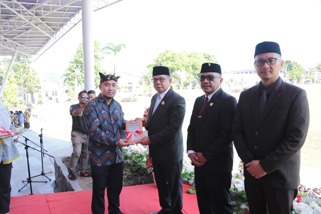 Tampak penulis buku perlawanan rakyat pedalaman Mongondow, Murdiono Mokoginta (kiri) saat menyerahkan buku kepada Pj Wali Kota Kotamobagu, Abdullah Mokoginta didampingi Ketua DPRD Kota Kotamobagu, Adrianus Mokoginta dan Sekretaris Kota Kotamobagu, Sofyan Mokoginta usai upacara peringatan Hari Pahlawan, Minggu 10 November 2024, di Lapangan Boki Hontinimbang Kotamobagu. Foto: dok/Bolmong.news